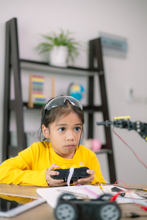 A young girl in a yellow shirt is playing with a remote control car. She is wearing goggles and she...