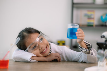 Asian child girl learning science chemistry with test tube making experiment at school laboratory....