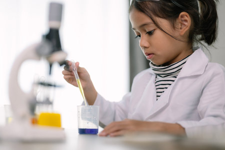 Asian child girl learning science chemistry with test tube making experiment at school laboratory....