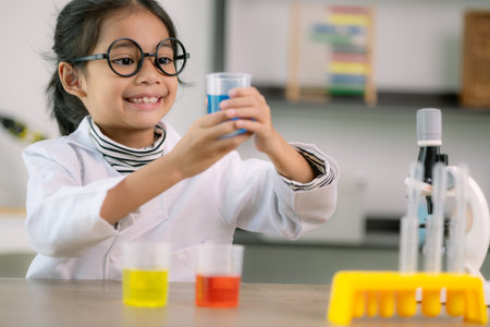 Little cute girl with a microscope holding a laboratory bottle with water experiment study...