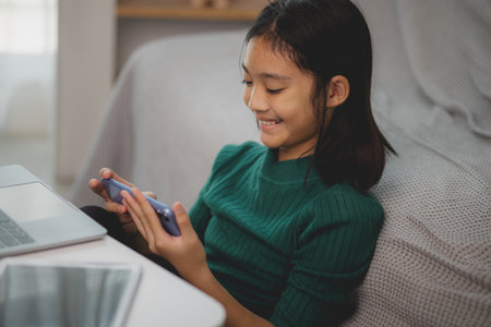 Asian young girls use mobile phones at home.の写真素材