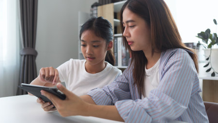 Two funny Asian girls laughing and sharing social media videos in a smart phone at homeの写真素材