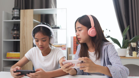 Asian kids play online video games with friends on mobile phones for fun at home.