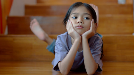 An Asian girl is lying on the stairs with a bored expression and looking around.の写真素材