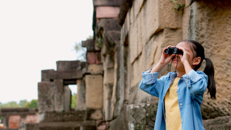 An Asian woman explores Phnom Wan Stone Temple using binoculars to admire its stunning architecture.の写真素材