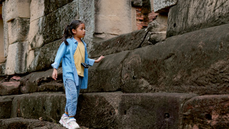 An Asian woman explores an ancient stone temple using binoculars to admire its stunning architecture.の写真素材