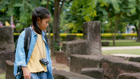 An Asian woman explores a stone temple using binoculars to admire its stunning architecture.の写真素材