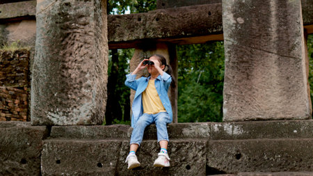 An Asian woman explores Phanom Wan Stone Castle using binoculars to admire its stunning architecture.の写真素材