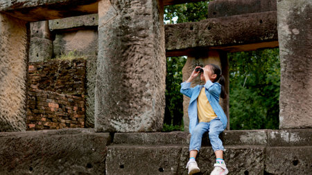 An Asian woman explores an ancient stone temple using binoculars to admire its stunning architecture.の写真素材