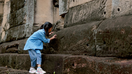 An Asian woman explores an ancient stone castle using binoculars to admire its stunning architecture.の写真素材