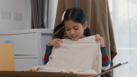 Asian little girls sorting clothes and packing into box. Donations for charity, help low income families, declutter home, sell online, moving moving into new home, recycling, sustainable livingの写真素材