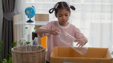 Asian little Girls dump plastic bottles in recycling boxes to reduce trash, reuse, and recycle. Recyclability and sustainability concept.の写真素材