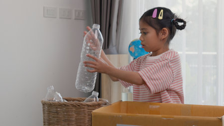 Asian little Girls dump plastic bottles in recycling boxes to reduce trash, reuse, and recycle. Recyclability and sustainability concept.の写真素材
