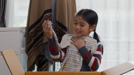Asian little girls sorting clothes and packing into box. Donations for charity, help low income families, declutter home, sell online, moving moving into new home, recycling, sustainable livingの写真素材