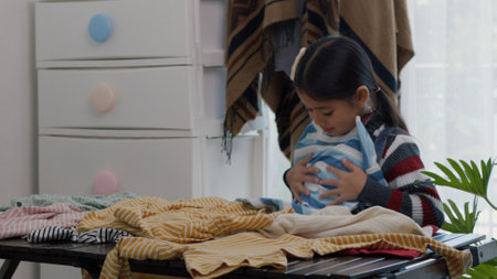 Asian little girls sorting clothes and packing into box. Donations for charity, help low income families, declutter home, sell online, moving moving into new home, recycling, sustainable livingの写真素材