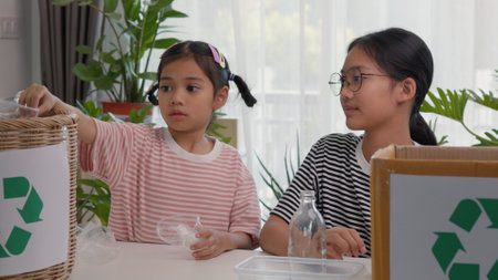 Asian siblings recycle household waste, Protect nature, and save the environment. children learn to sort garbage by putting plastic bottles in the recycleの写真素材