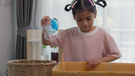 Asian little Girls dump plastic bottles in recycling boxes to reduce trash, reuse, and recycle. Recyclability and sustainability concept.の写真素材