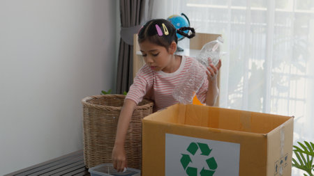 Asian little Girls dump plastic bottles in recycling boxes to reduce trash, reuse, and recycle. Recyclability and sustainability concept.の写真素材