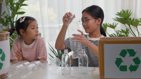 Asian siblings recycle household waste, Protect nature, and save the environment. children learn to sort garbage by putting plastic bottles in the recycleの写真素材