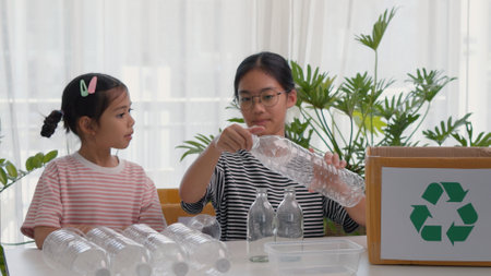 Asian siblings recycle household waste, Protect nature, and save the environment. children learn to sort garbage by putting plastic bottles in the recycleの写真素材