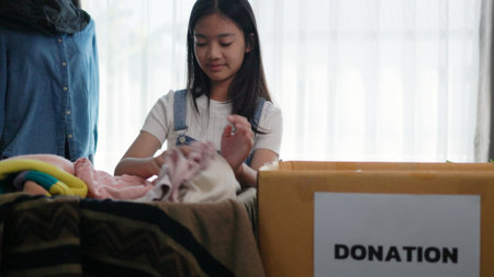 Recycling, Donation for poor, Asian girls packing objects at home, putting on stuff into donate box with second hand clothes, charity helping and needy people. Reuse recycle, moving.の写真素材