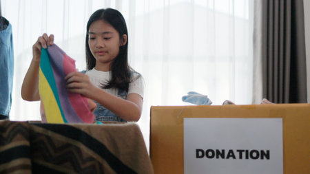 Recycling, Donation, Asian girls packing objects at home, putting on stuff into donate box with second hand clothes, charity helping needy people. Reuse recycle, moving.の写真素材