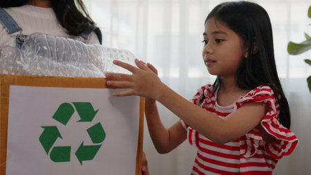 Asian little Girls dump plastic bottles in recycling boxes to reduce trash, reuse, and recycle. Recyclability and sustainability concept.の写真素材