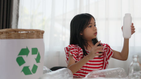 Asian little Girls dump plastic bottles in recycling boxes to reduce trash, reuse, and recycle. Recyclability and sustainability concept.の写真素材