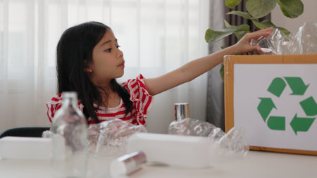 Asian little Girls dump plastic bottles in recycling boxes to reduce trash, reuse, and recycle. Recyclability and sustainability concept.の写真素材
