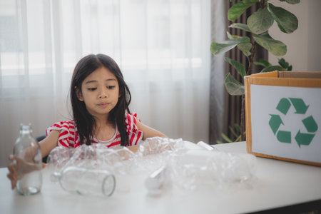 Asian little Girls dump plastic bottles in recycling boxes to reduce trash, reuse, and recycle. Recyclability and sustainability concept.の写真素材
