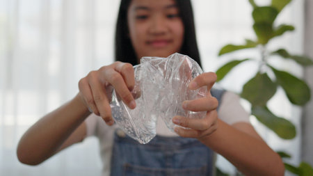 Asian girl crumples plastic water bottles to recycle.の写真素材