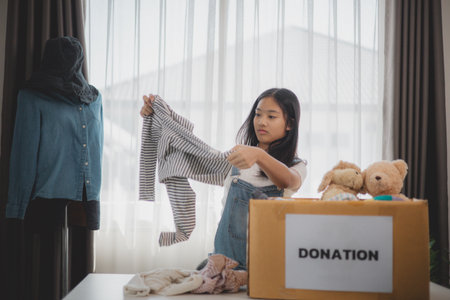 Recycling, Donation for poor, Asian girls packing objects at home, putting on stuff into donate box with second hand clothes, charity helping and needy people. Reuse recycle, moving.の写真素材