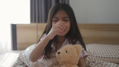 The scared little girl in the bedroom crying with her hands holding her teddy in fear of monsters in darkness in the bedroom in the Child's nightmares imagination and psychological distress concept.の写真素材