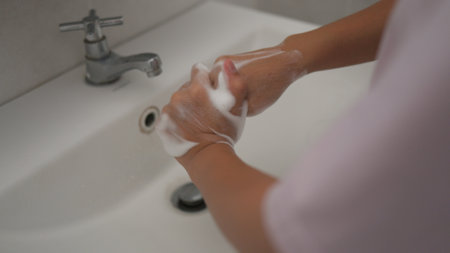 Little girl washing hands with water and soap in the bathroom. Happy kid showing soapy palms. Hands hygiene and virus infection prevention.の写真素材