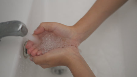Little girl washing hands with water and soap in the bathroom. Happy kid showing soapy palms. Hands...