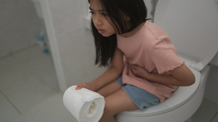 Asian girls suffer from diarrhea their stomach is painful. ache and problem. hand holds tissue paper roll in front of toilet bowl. constipation in the bathroom.の写真素材