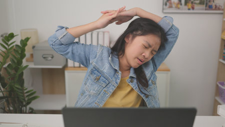 Relax Asian girl teenager stretching her arms above her head relaxing resting at a co-working space.