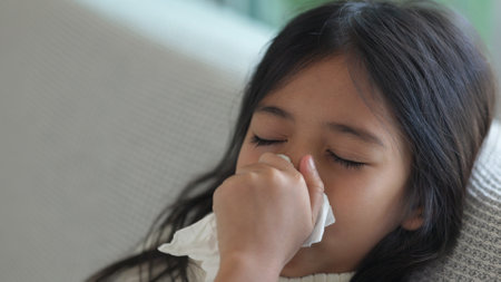 Asian child girl sick with sneezing on the nose and cold cough on tissue paper because weak or virus and bacteria from dust weather and Air pollution pm2.5の写真素材