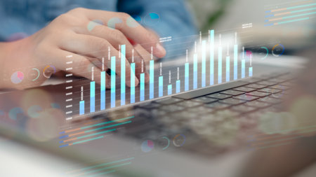 Close-up of hands on laptop keyboard with digital analytics dashboard, bar chart, and data...