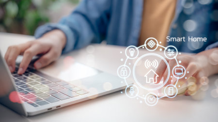 Smart home technology concept with person using laptop to control home automation system, showing icons for IoT devices and wireless connectivity in modern lifestyle.の写真素材