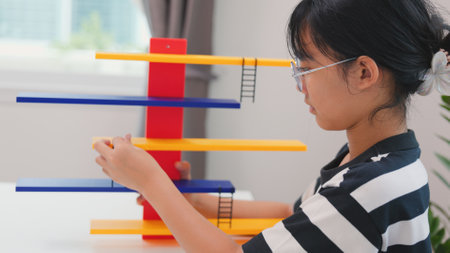 Asian girl learning STEM by assembling mechanical parts with focus and determination. Concept of...