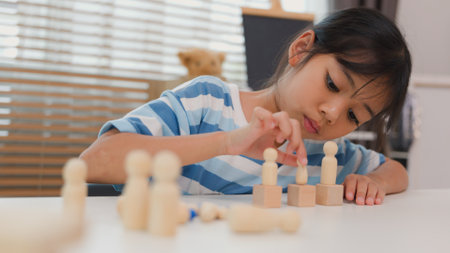 Young Asian girl focused on stacking wooden blocks, promoting STEM learning, creativity, and motor skill development. Concept of early education, problem solving, and cognitive growth.の写真素材