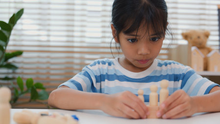 Young Asian girl focused on stacking wooden blocks, promoting STEM learning, creativity, and motor skill development. Concept of early education, problem solving, and cognitive growth.の写真素材