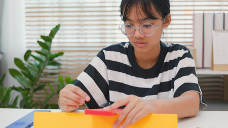 Asian girl assembling a colorful plastic structure with a screwdriver as part of a STEM learning activity. Concept of hands-on education, child engineering, creativity, and problem solving.の写真素材