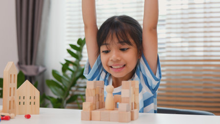 Young Asian girl focused on stacking wooden blocks, promoting STEM learning, creativity, and motor skill development. Concept of early education, problem solving, and cognitive growth.の写真素材