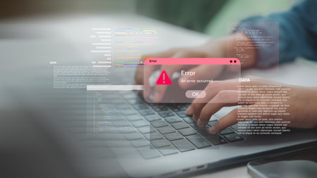 Hands typing on laptop with coding error alert popup, representing software bugs, programming...