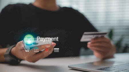 Person using smartphone and credit card for secure online payment, with holographic icons representing mobile banking, e-commerce, financial technology, and global digital transaction system.の写真素材