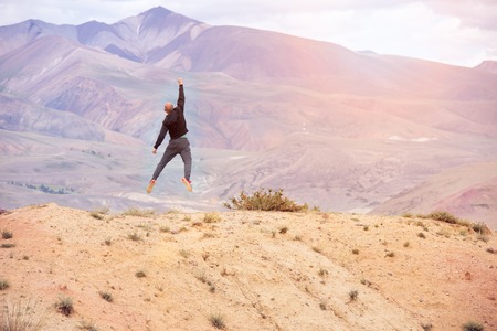 bald man jumping on top of a mountain of joyの写真素材