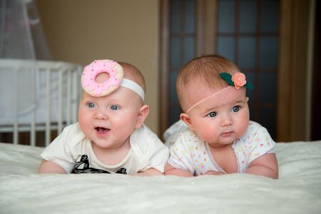 twin baby boy and girl lie on the bed and smile