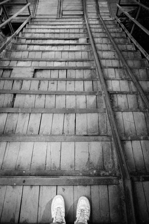 Male legs stand on old wooden and metal stairsの写真素材